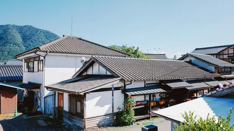 青空の下、山あいに瓦屋根の住宅が建ち並ぶ町並み