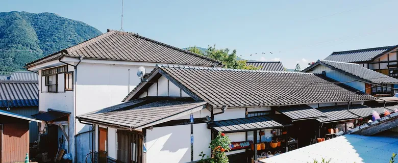 青空の下、山あいに瓦屋根の住宅が建ち並ぶ町並み